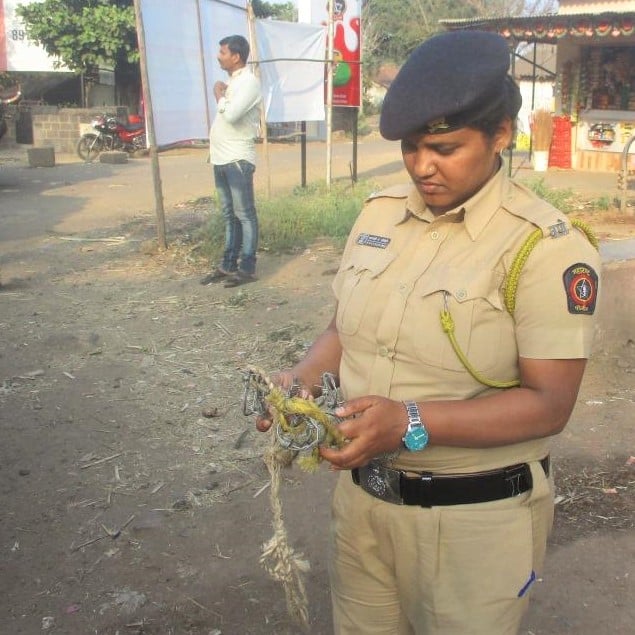 A police officer looks disapprovingly at the confiscated torture devices made of barbed wire that she holds.