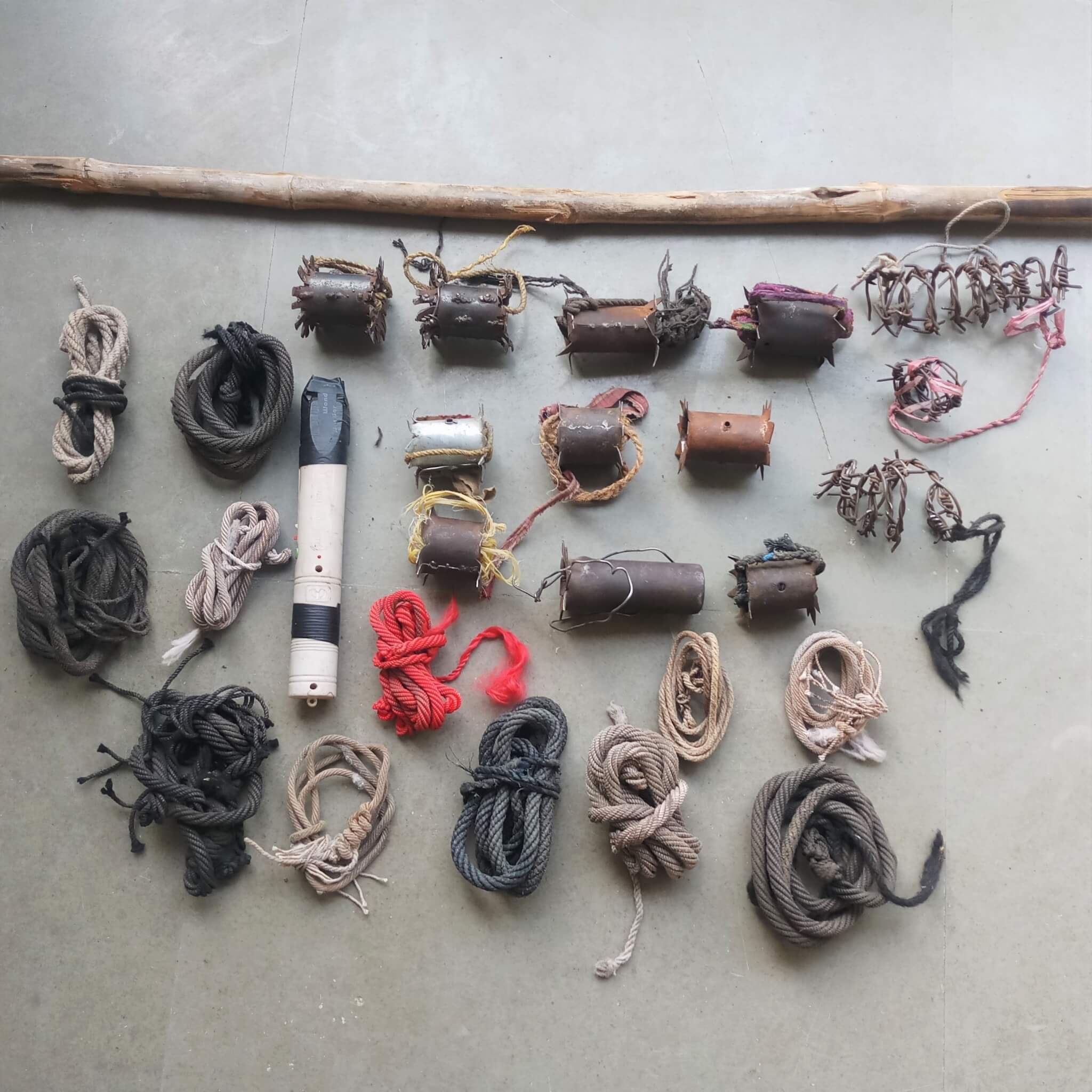 An array of cruel devices is laid out, including a stick, nose ropes, and barbed-wire and metal yoke spikes.