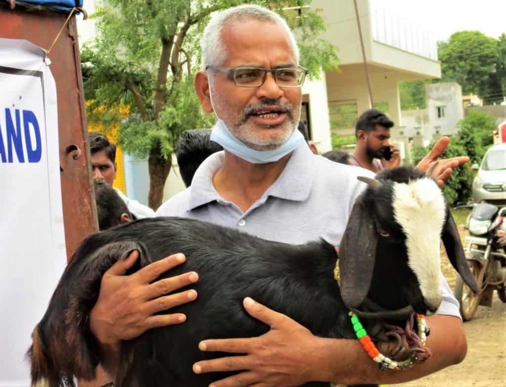 An Animal Rahat staff member cuddles a small goat.