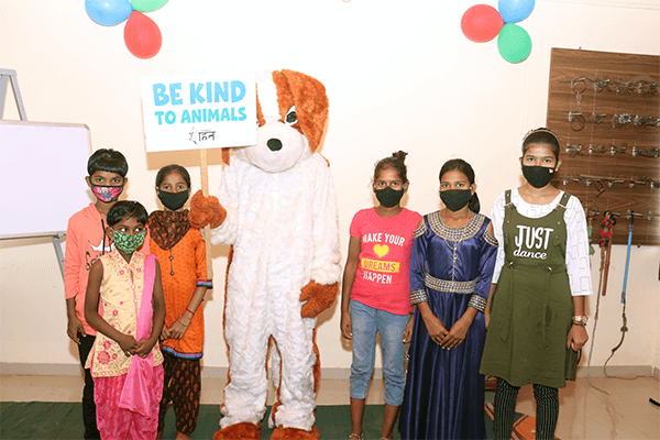 Students at the Sangli sanctuary’s education center pose with a “dog” mascot.