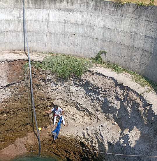 An Animal Rahat team member rappels into the deep well to rescue the jackal.